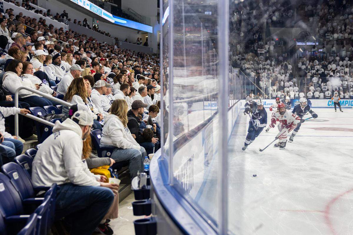 Attendees watch as players chase after the puck during the women’s hockey Frozen Four game between the Penn State and Wisconsin in Pegula Ice Arena on Friday, March 20, 2026.