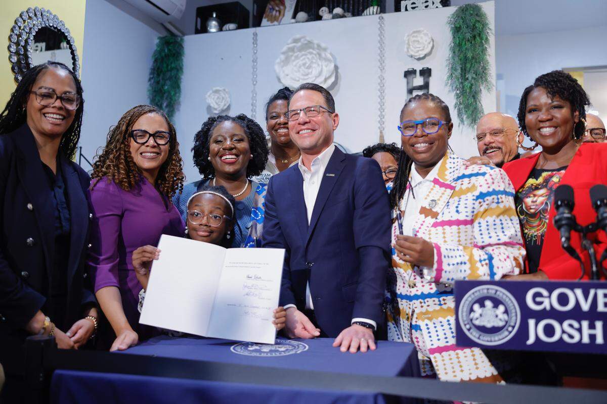 Gov. Josh Shapiro poses with elected officials in Philadelphia after signing the CROWN Act into law Nov. 25, 2025. It’s one of several new laws taking effect in Pennsylvania in January.