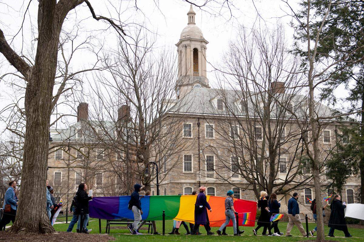 A large Pride flag is marched past Old Main Monday during a Pride march and rally at Penn State.