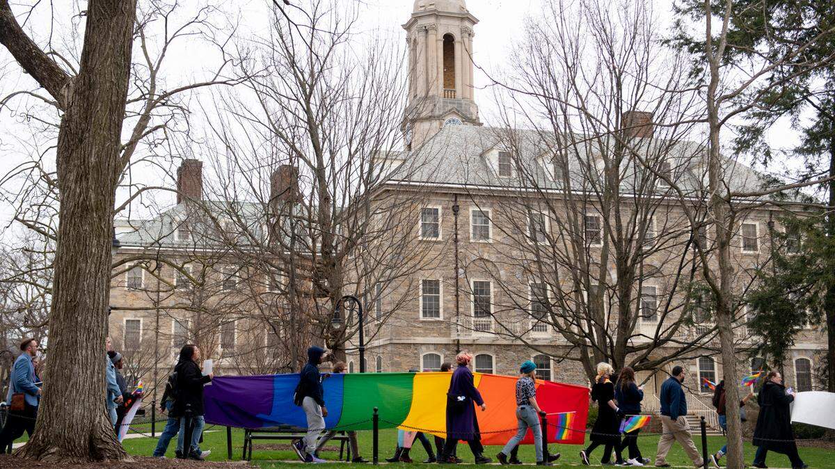 A large pride flag is marched past Old Main during a pride event at Penn State on Monday, April 11, 2022 in University Park, Pa.