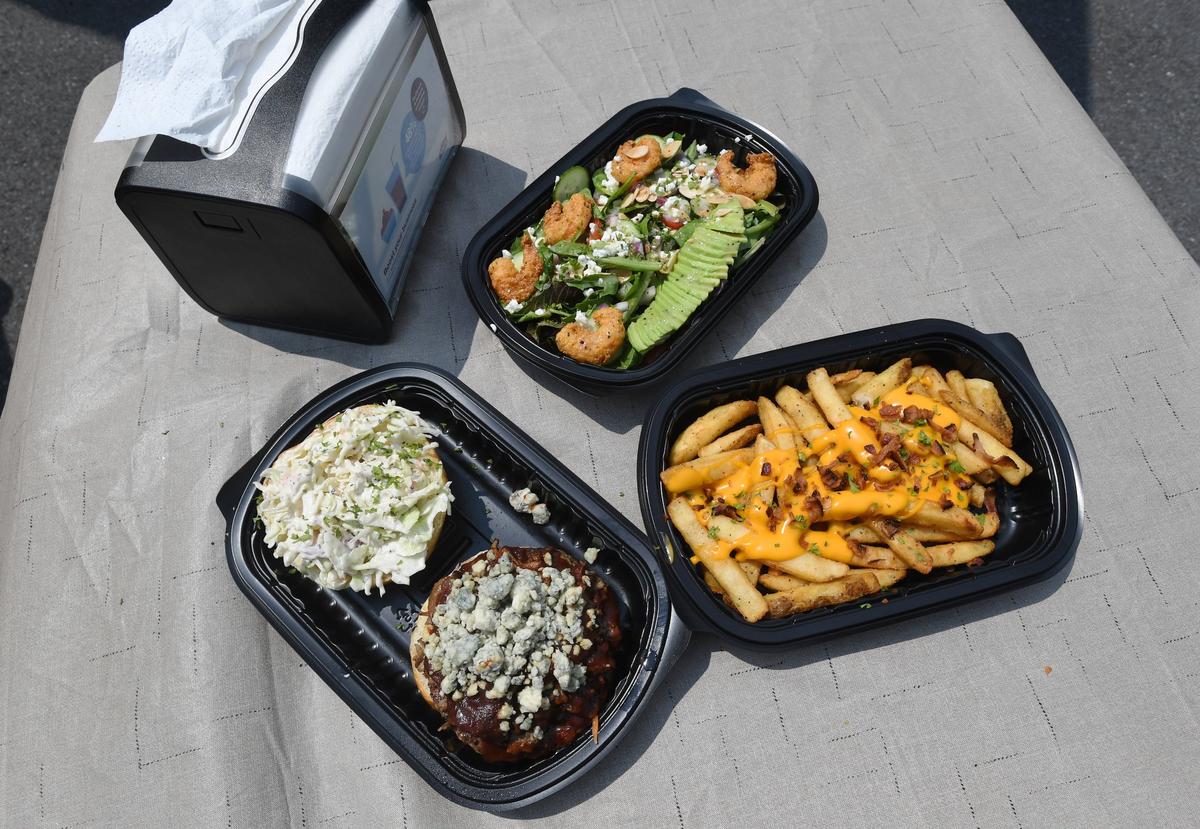 An avocado salad, cheesy fries and “The Happy Burger” are prepared at the Happy Dishes food trailer.