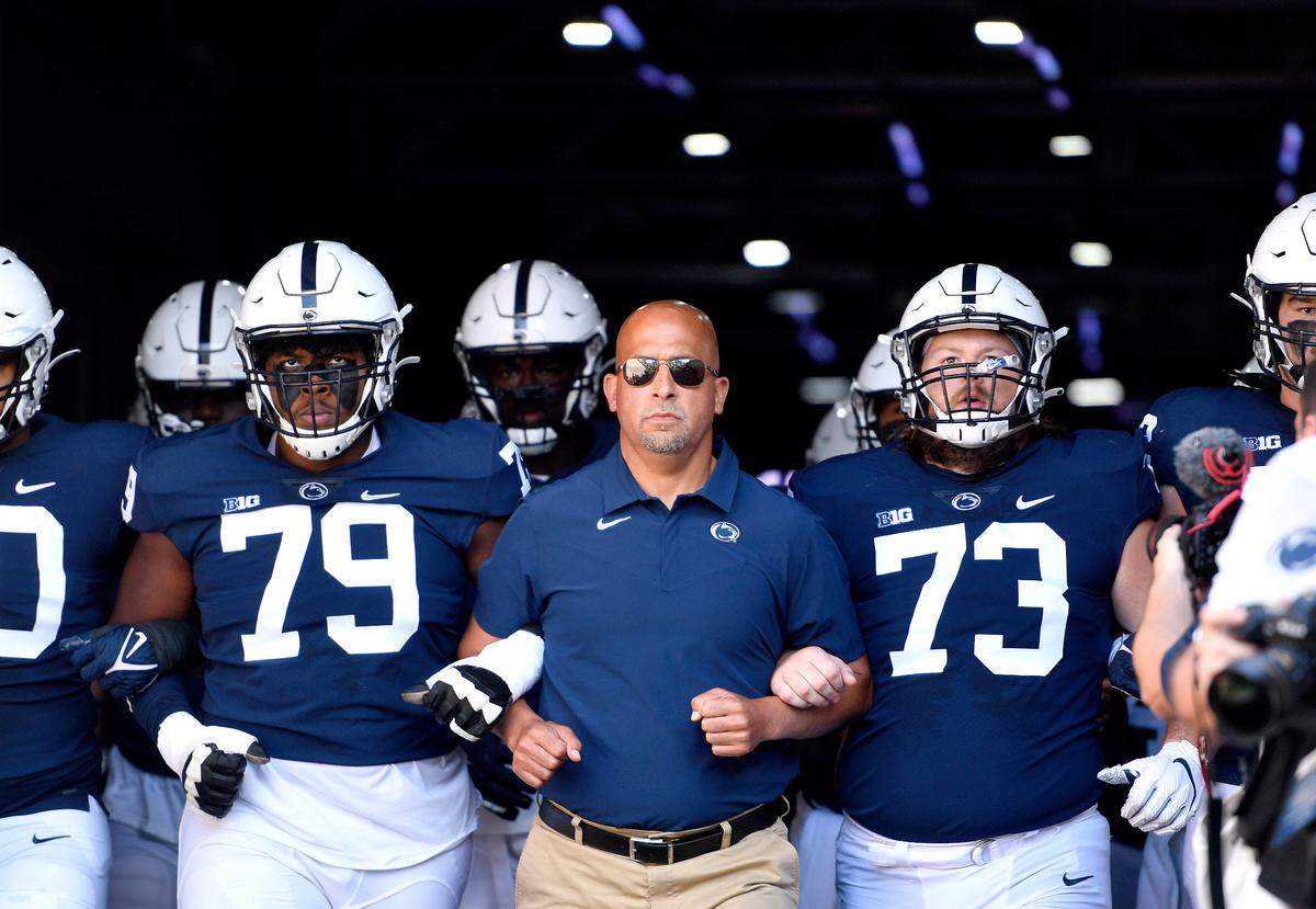 Penn State offensive linemen Caedan Wallace (left) and Mike Miranda link arms with coach James Franklin to walk out of the tunnel for the game against Ball State on Saturday, Sept. 11, 2021.
