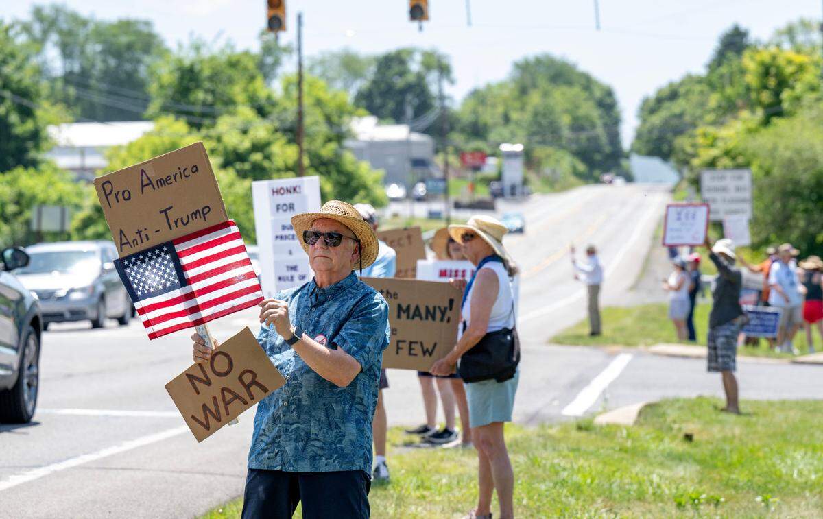 Rick Sargo holds a sign that reads “Pro America Anti-Trump” as he and other protesters gather outside of U.S. Rep. Glenn Thompson’s office on Tuesday, June 24, 2025.