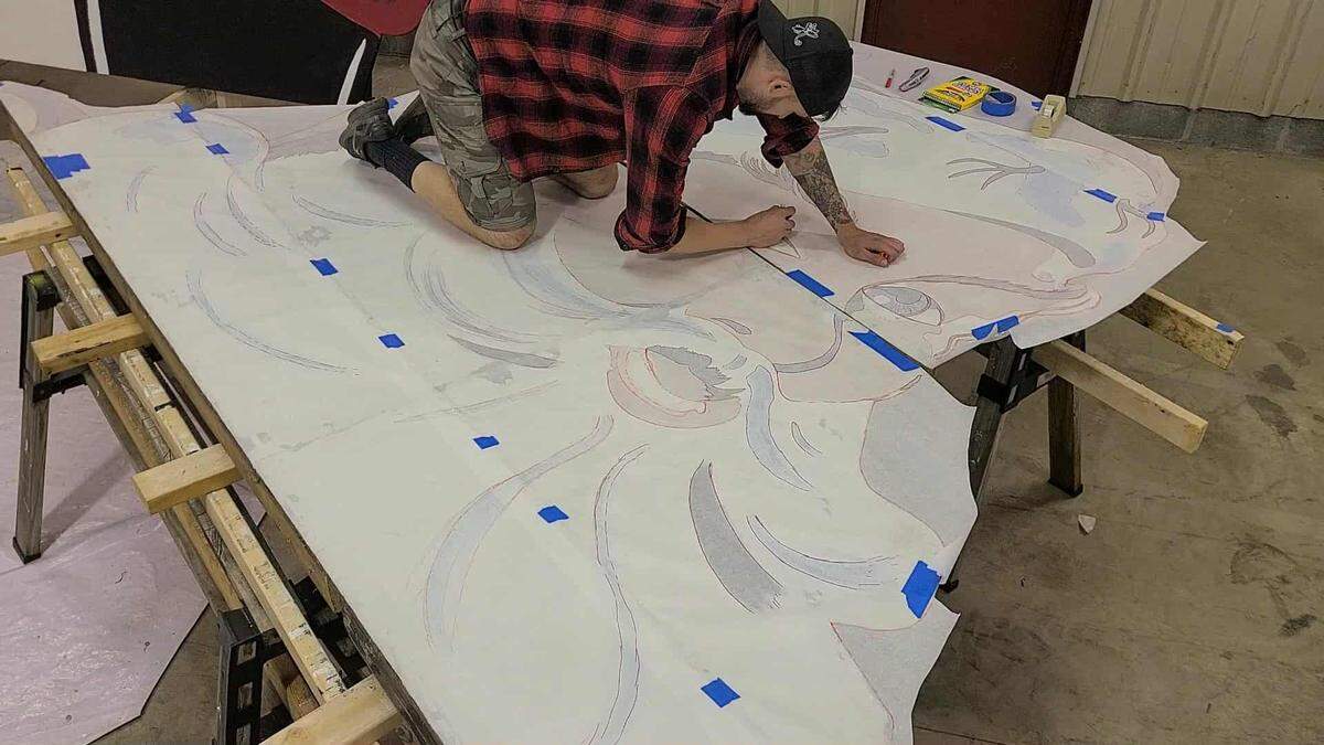 Tyler Walstrom uses tracing paper to copy the design of the iconic Philipsburg Santa. 
