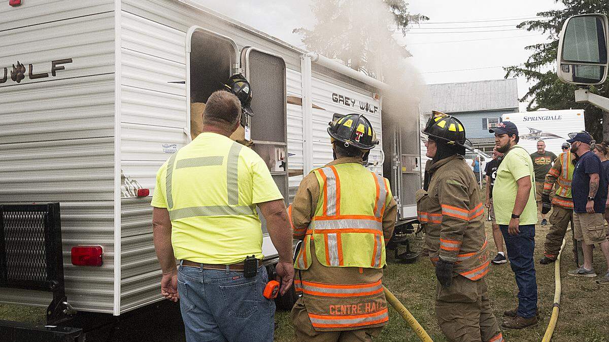A Centre Hall firefighter stands in the rear doorway pulling down the ceiling as a trailer is vented of smoke on Sunday at the Grange fairgrounds. A camper owned by Joel and Kristi Brinker of Spring Mills caught fire. People were moving in for the Grange Fair, which runs Aug. 19-27.