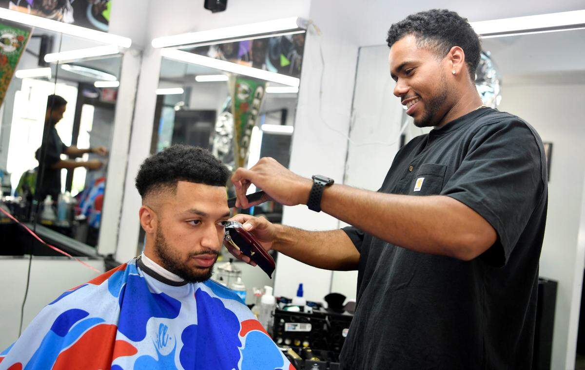 Spencer Haley, a barber at The Pregame Barbershop gives a haircut to Ashton Baker on July 21. The barbershop has given Haley and opportunity to start Walks on Water Kicks, a buy, sell and trade shoe store.