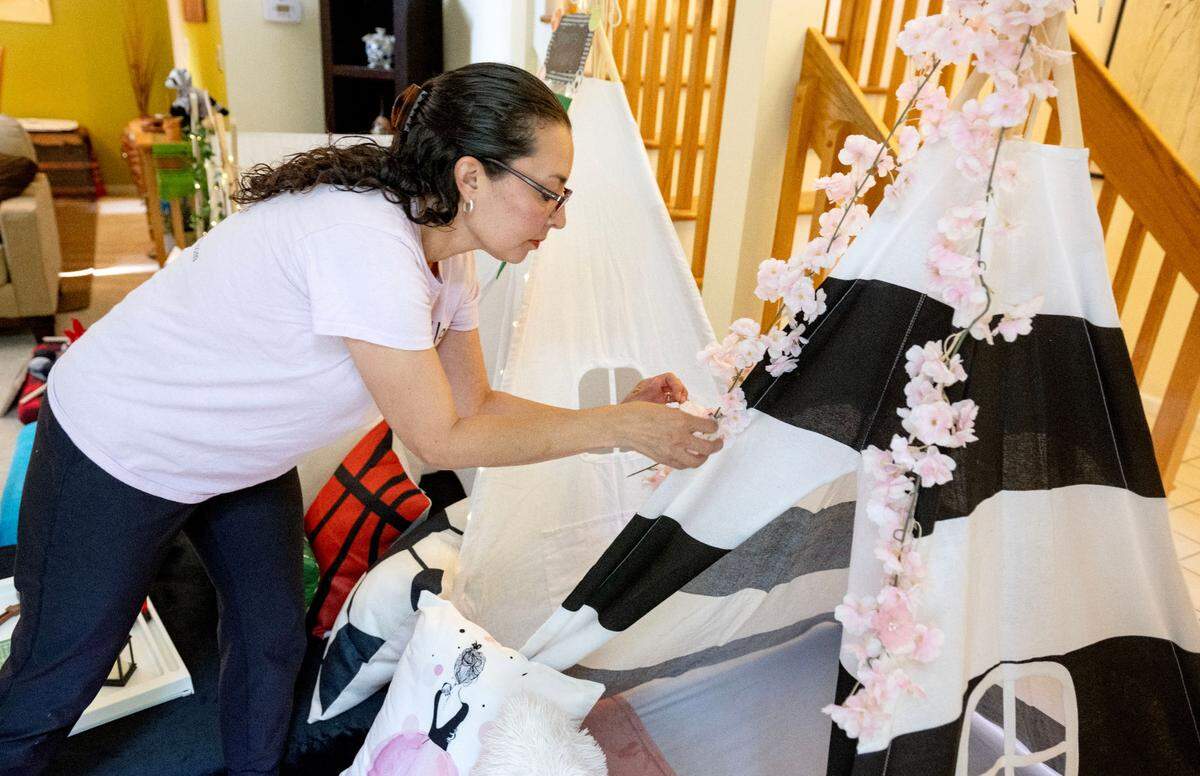 Claudia Prieto of Happy Valley Slumber hangs flowers on a tent for the Night in Paris theme.