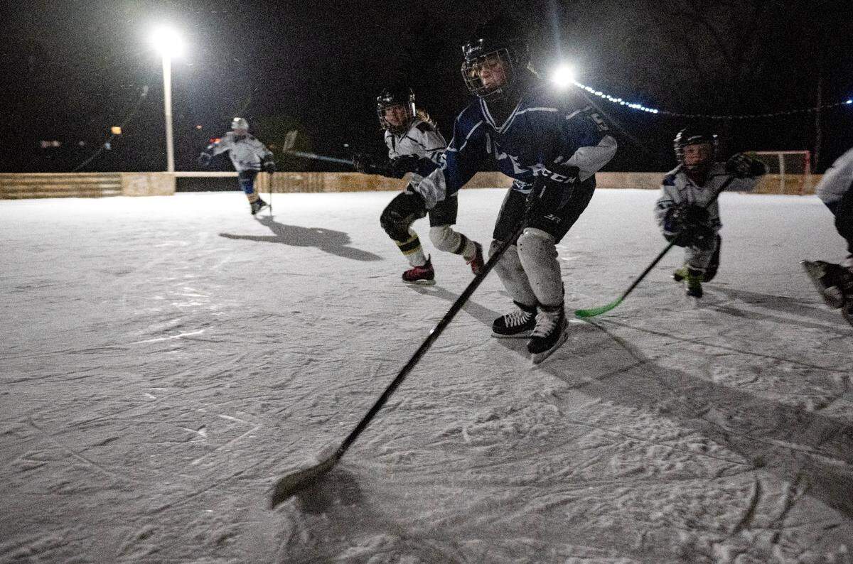 Gabriel Wess skates down the ice with the puck as he plays with his friends on the ice rink in Bill Dickson’s back yard in Lemont on Thursday, Feb. 20, 2025.