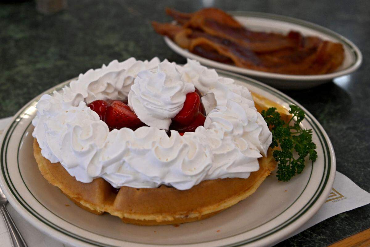 A strawberry waffle and a side of bacon at the Waffle Shop in Bellefonte on Friday, March 10, 2023.