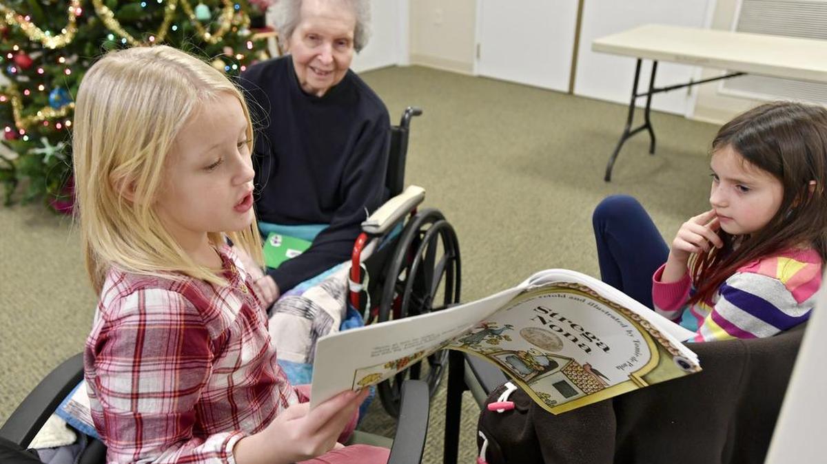 Tiffany Oswalt, a third-grader at Philipsburg Elementary, reads to Marion Alexander at Windy Hill Village on Dec. 8. Once a month, students from the elementary school walks over to read to residents.