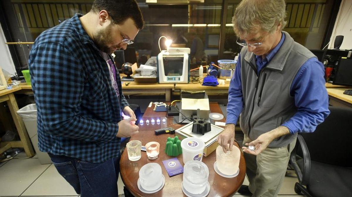 Eric Furjanic and John Stitzinger place small lights into ice luminaries at the Make Space on Wednesday.