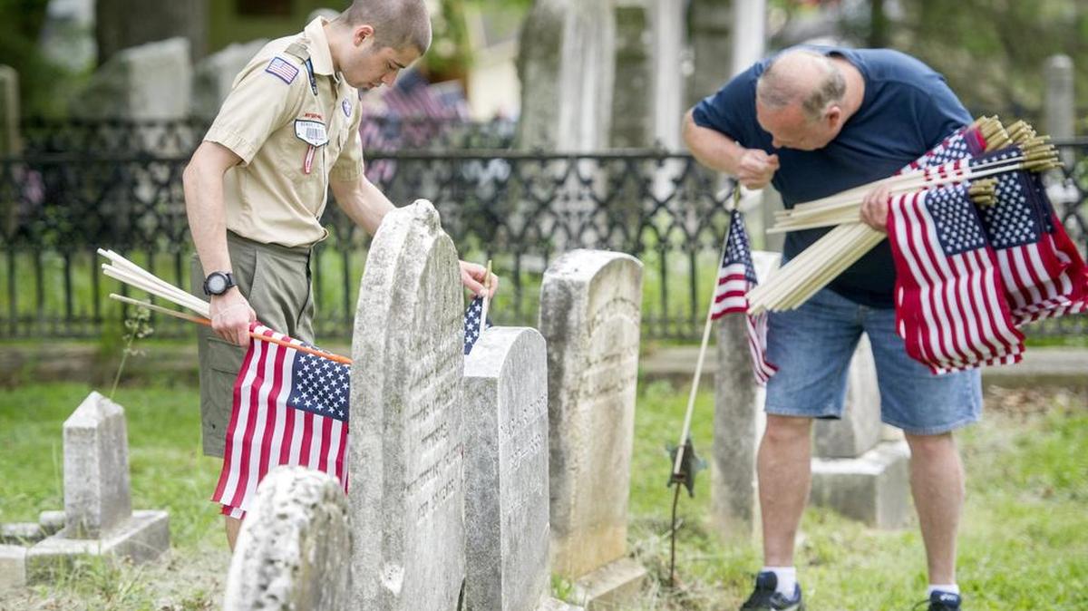 Seth Balkey, 19, places flags on graves of veterans.
