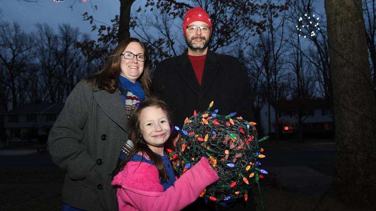 David Stone, right, Melissa Stone and their daughter Abby Stone, 6, smile for a portrait with a multicolored ball of light made from chicken wire on Tuesday in their neighborhood in Park Forest.
