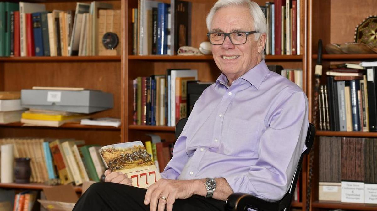 Retired Penn State professor Dean Snow poses with his book, “1777: Tipping Point at Saratoga,” in his study in his State College home.