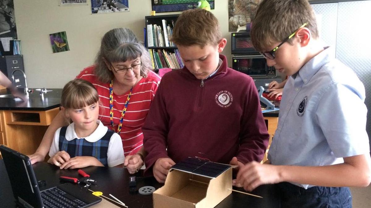Under the guidance of science teacher Lisa Groves, OLV middle school students Timothy Peters and Sammy Viglione show elementary school student Claire Peters how they are engineering a solar car.