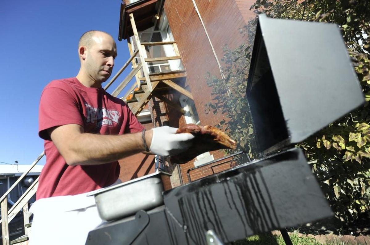 Justin Leiter places a beef brisket on a smoker outside of the Red Horse Tavern in Pleasant Gap in 2012.