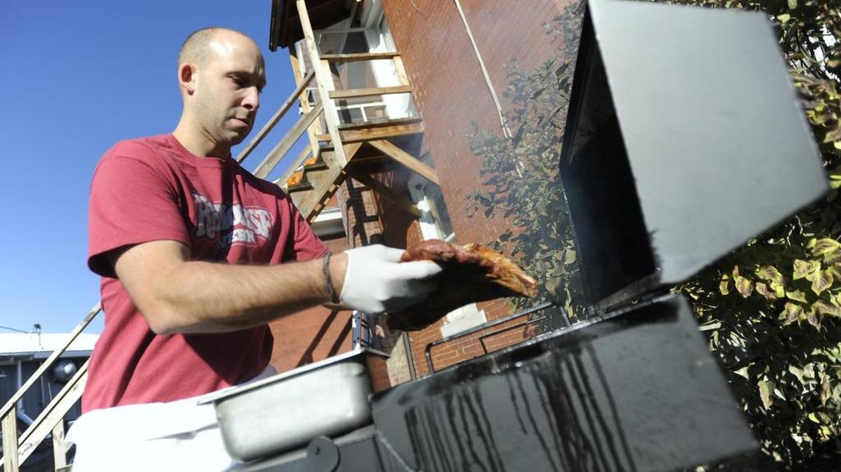 Justin Leiter places a beef brisket on a smoker outside of the Red Horse Tavern in Pleasant Gap in 2012.