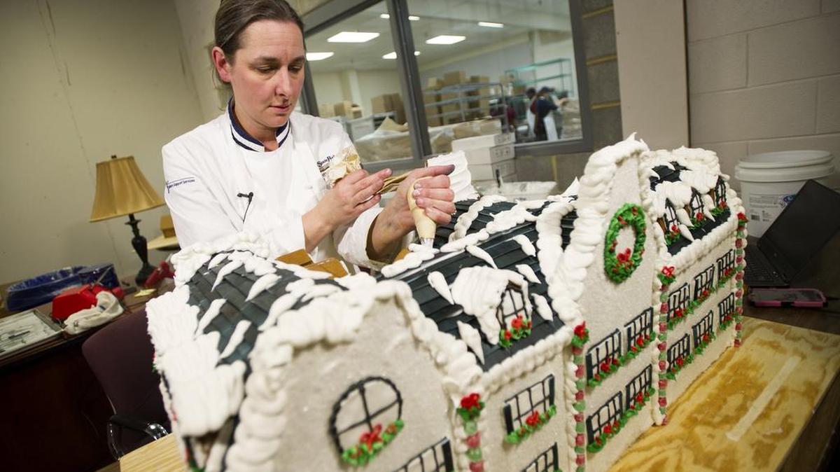 Heather Luse, executive pastry chef at the Penn State Bakery, works on the Nittany Lion Inn gingerbread house on Dec. 9.