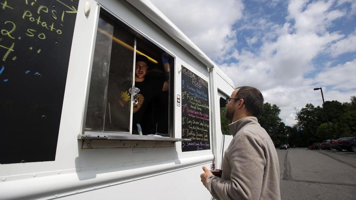 Food for Thought owner Mitch Angle, left, listens to Eric Lysczek’s order on Thursday at the AccuWeather parking lot.