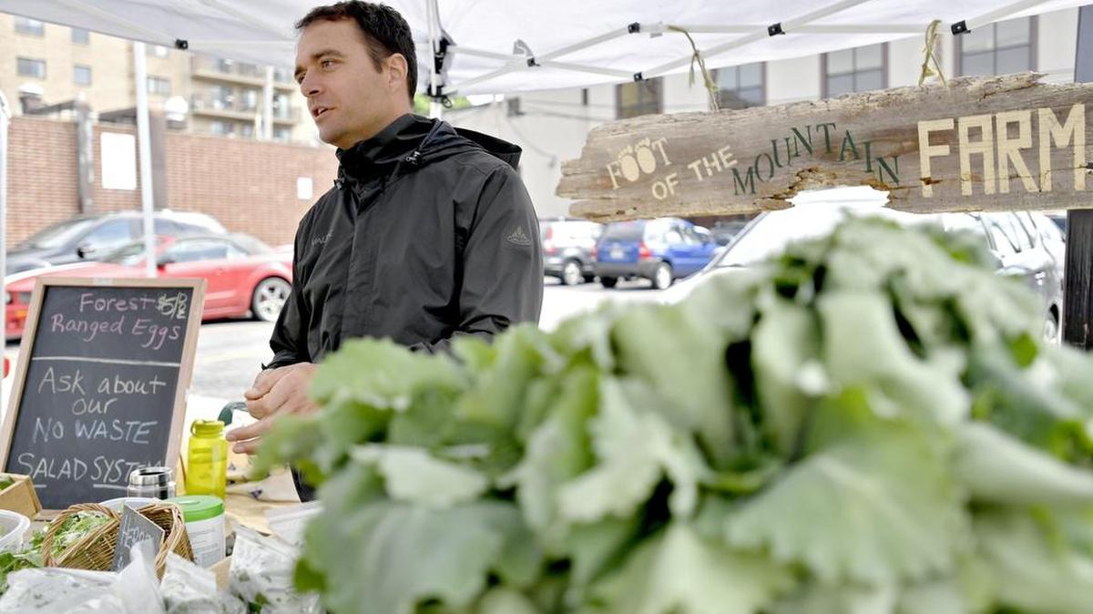 Lorenzo Varisano chats with customers as he’s surrounded by fresh kale, lettuce and herbs from Foot of the Mountain Farm at the Tuesday downtown State College farmers market on May 10.