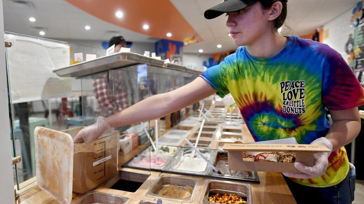 Fran O’Neill frosts and tops doughnuts on Wednesday at Peace, Love and Little Donuts in State College.