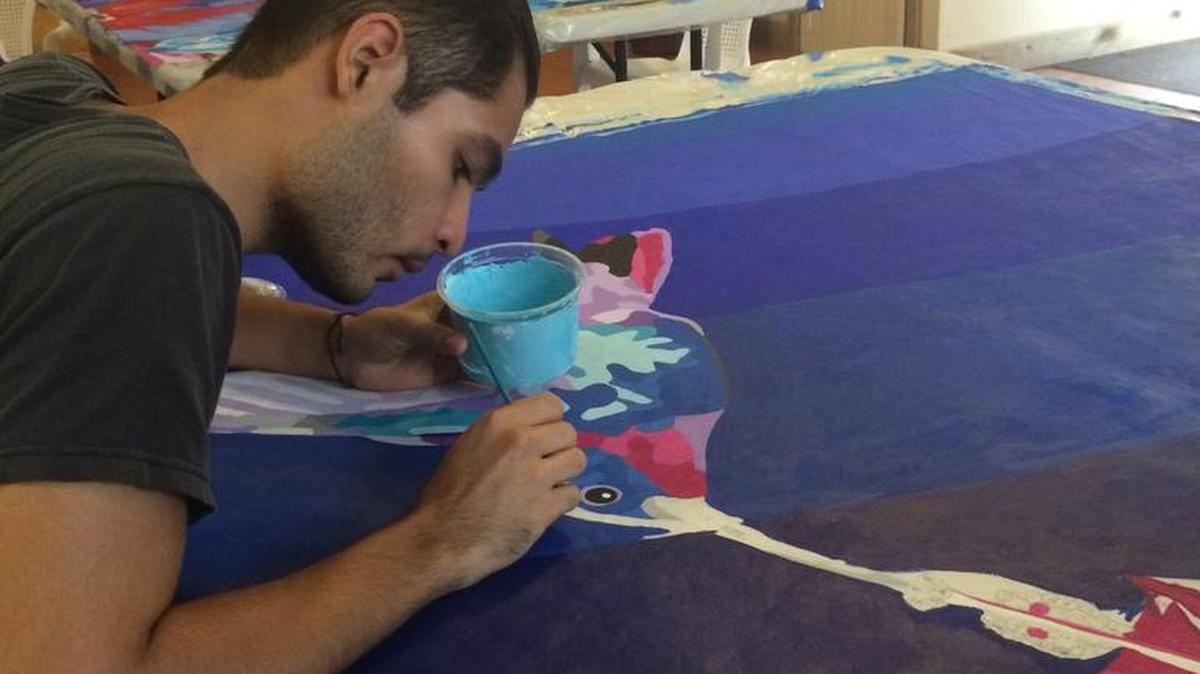 Galen University student Pablo Cambranes, who took many of the photographs used for the portraits in the Belize mural, paints a giant hummingbird for those who contributed at the hummingbird sponsorship level to the Kickstarter campaign.