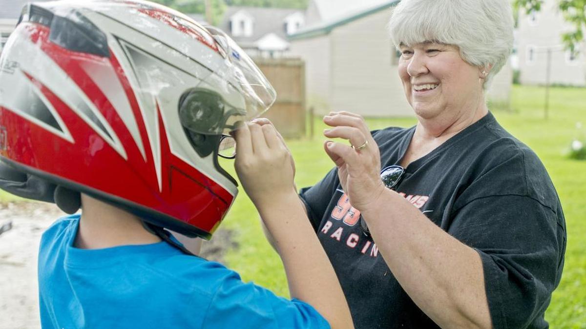Beth Haupt helps her 10-year-old grandson Aidan Adams put on his racing helmet. Aidan races go-karts, but donates part of his financial winnings to his Relay for Life team for his grandmother.