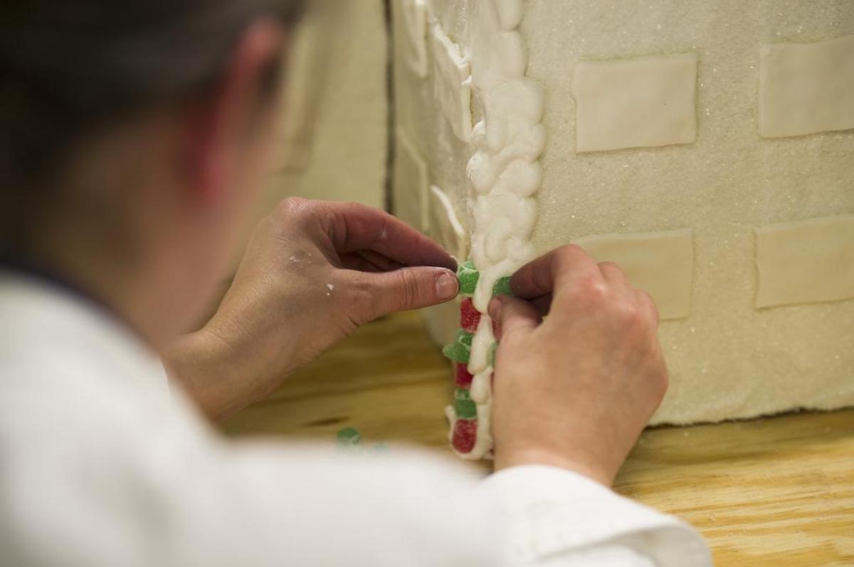 Heather Luse, executive pastry chef at the Penn State Bakery, adds gumdrops to a Nittany Lion Inn gingerbread house in December 2015.