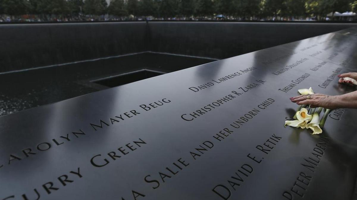 A visitor to the National September 11 Memorial arranges flowers on the north pool in September 2016, in New York.