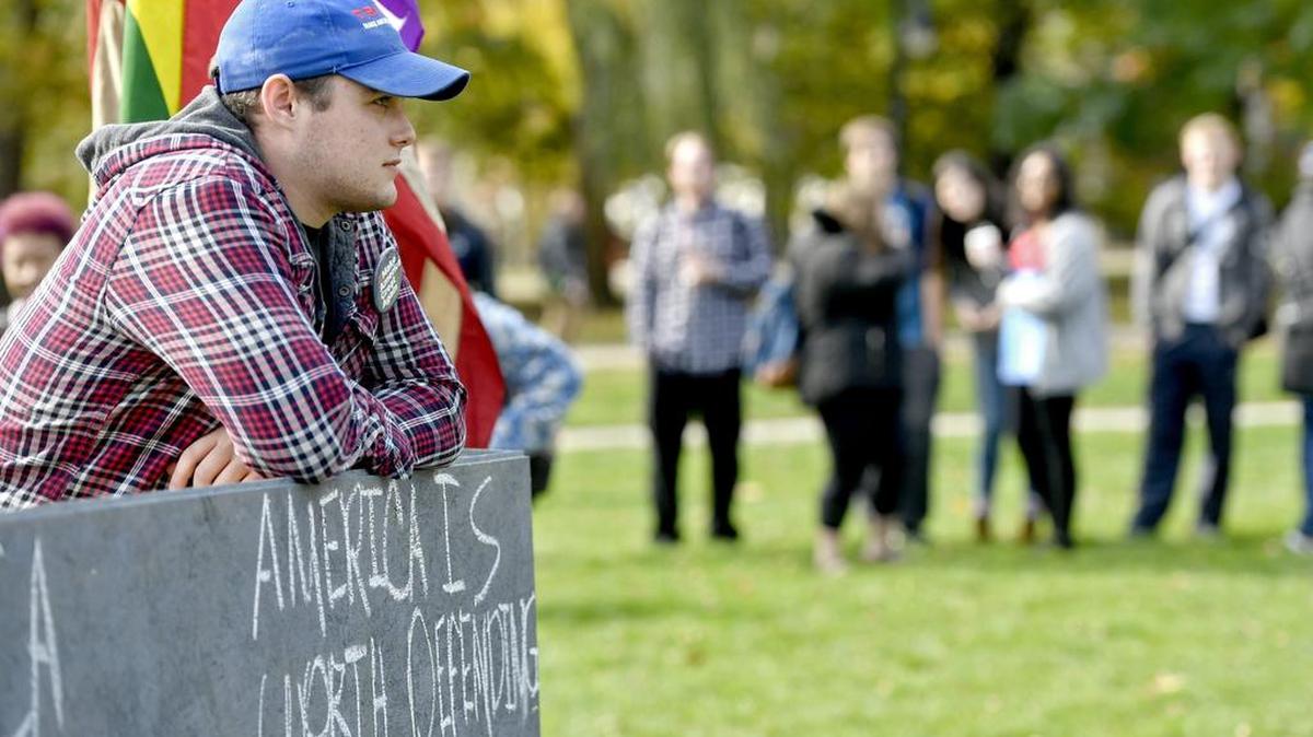 A crowd gathers as Jake Metzer and fellow Donald Trump supporters wait for students to walk up to chat to them at the wall they built around the American flag on the Old Main lawn on Tuesday.
