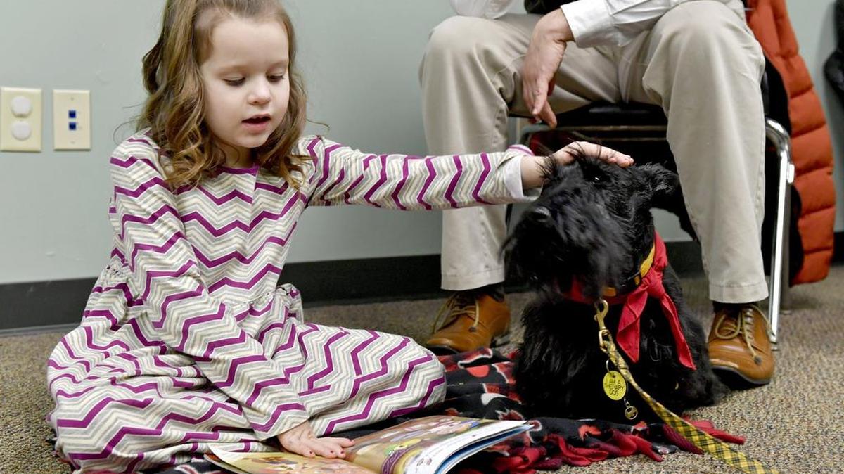 Madelyn Williams pets Scottish terrier and therapy dog Faolin as she reads him a book during a Tail Waggin’ Tutor session at the Centre County Library on Feb. 7.