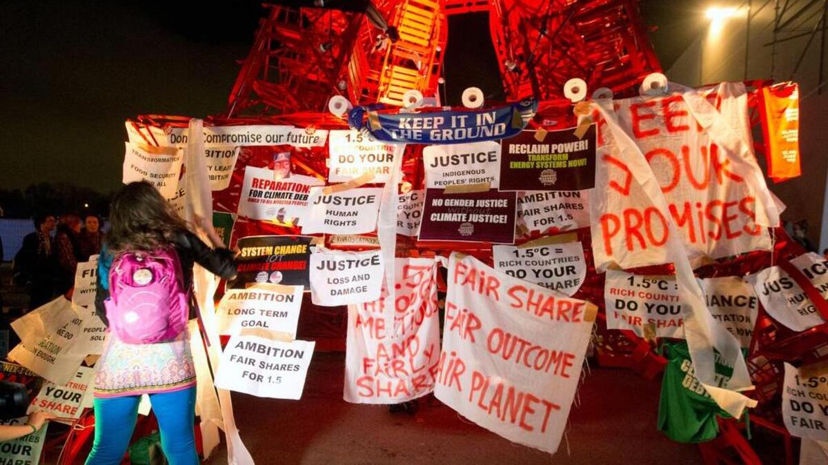 A participant puts posters on the mini red Eiffel Tower as NGO representatives staged a sit-in protest closed to the plenary session to denounce the first draft COP21 Climate Conference agreement in December 2015.