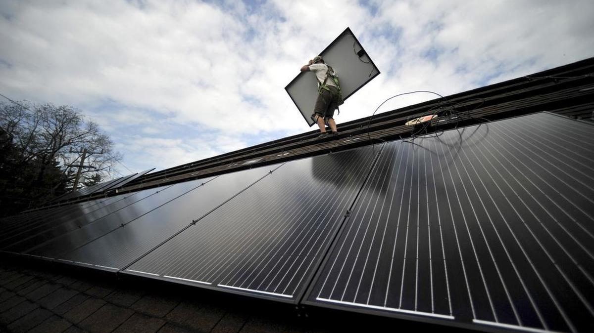 Jason Grottini of Envinity moves a solar panel into place on the roof of the State College Friends Meeting in State College on Sept. 9.