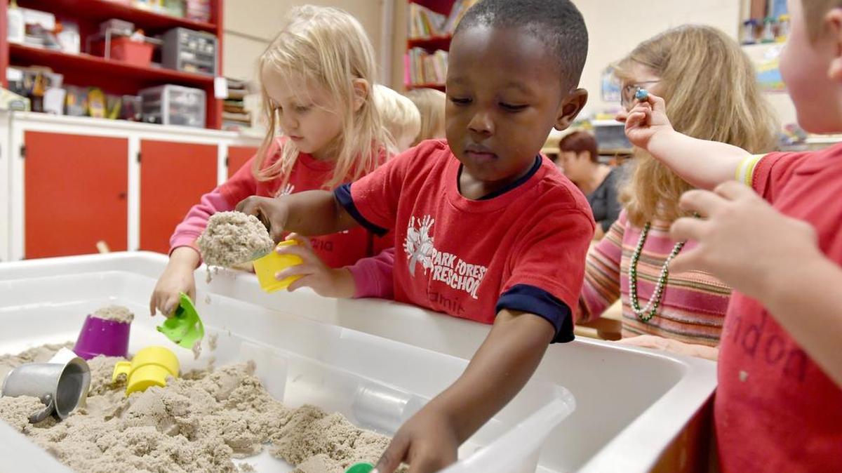 Jamir, 3, looks for acorns buried in a sandbox at Park Forest Preschool on Friday.