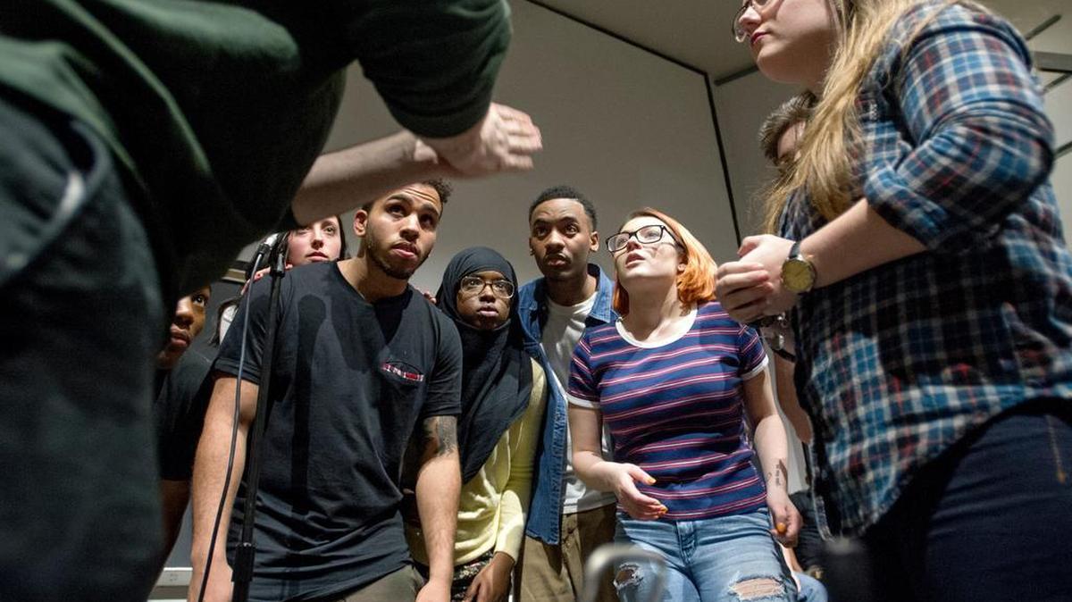 Members of the Penn State Slam Poetry team and the Rowan team listen to the finals rules before a slam on March 24 in the Thomas Building.