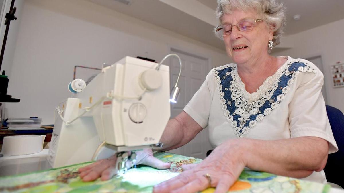 Artist Pat Dolan, a member of Fibers Unlimited, shows how she creates designs on her pieces with a special type of foot on her sewing machine in her home studio.