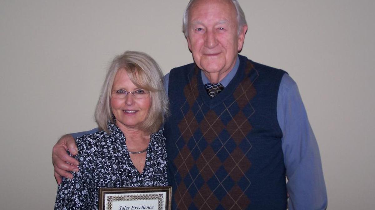 George Parmer, right, owner of Fine Line Homes, presents the sales award to housing consultant Cindy Stern.