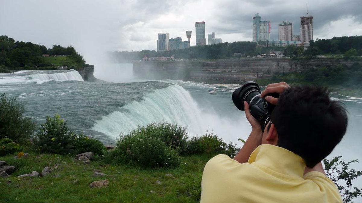 A tourist snaps photos of Niagara Falls from the New York side.