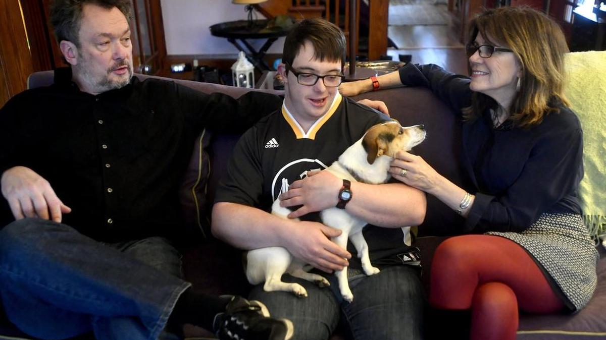 Jamie Berube holds Becca as he sits with his parents, Michael and Janet Berube, on Wednesday. Michael Berube authored “Life as Jamie Knows It” about his son’s journey into adulthood with Down syndrome.