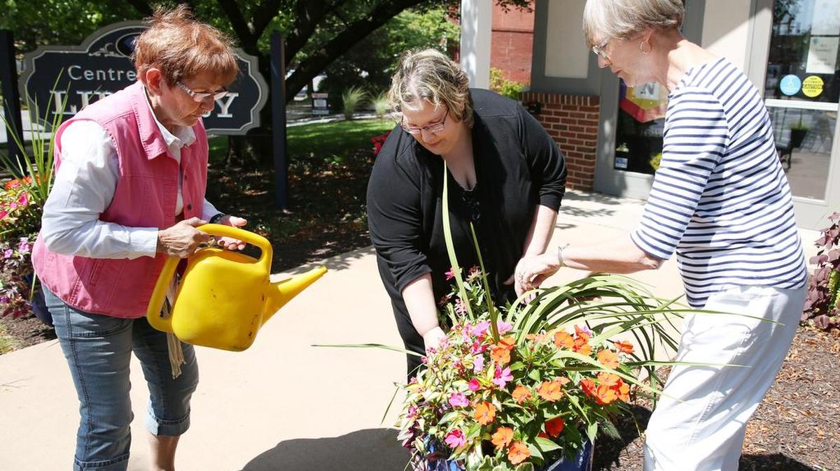 Members of the Bellefonte Garden Club, Ann Sager, left, Lisa Erickson, center, and Wilda Stanfield tend to potted plants outside of the Centre County Library and Historical Museum on Tuesday in Bellefonte.
