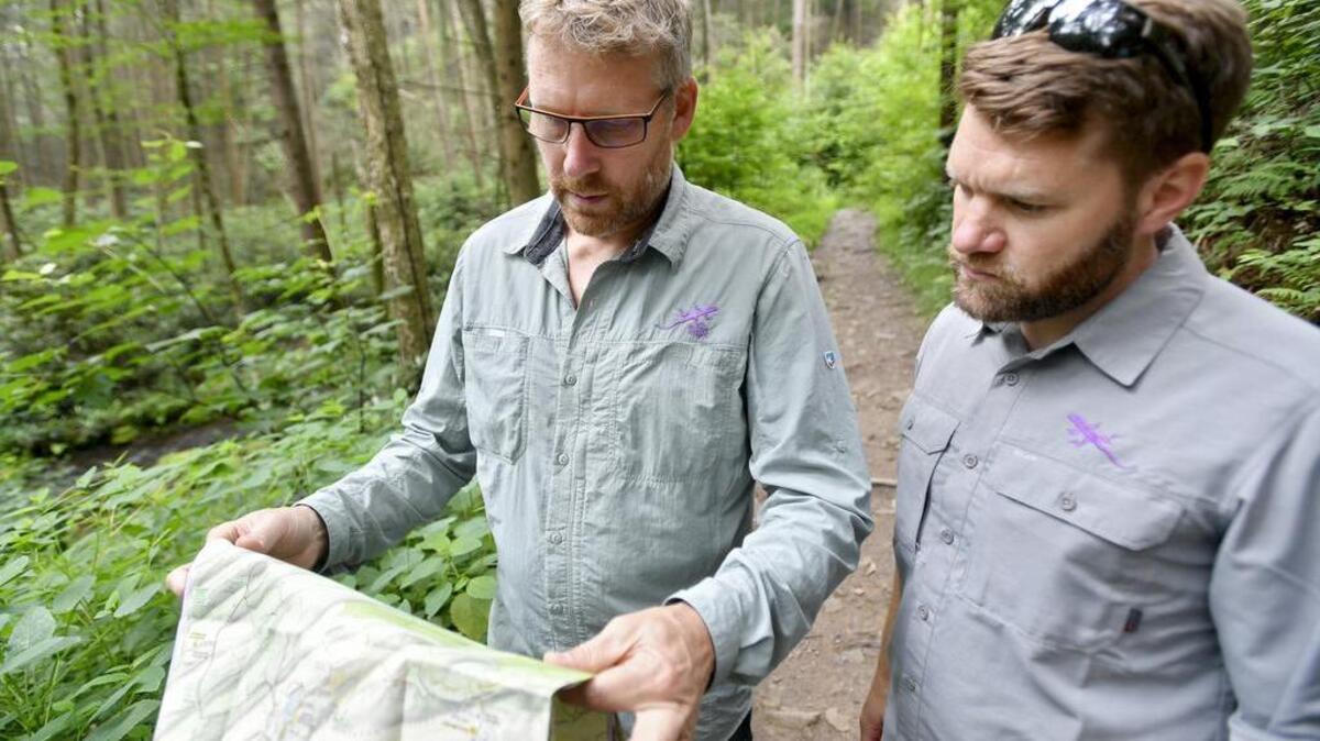 Michael Hermann and Dave Gantz of Purple Lizard Maps look for one of their favorite spots on the Rothrock Trail map on July 27 in Rothrock State Forest.