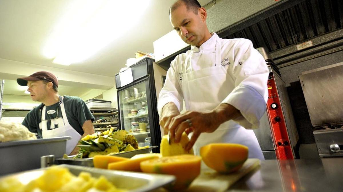 Mike Benjamin, of Benjamin’s Catering, cuts fruit at the Pleasant Gap kitchen on Thursday.