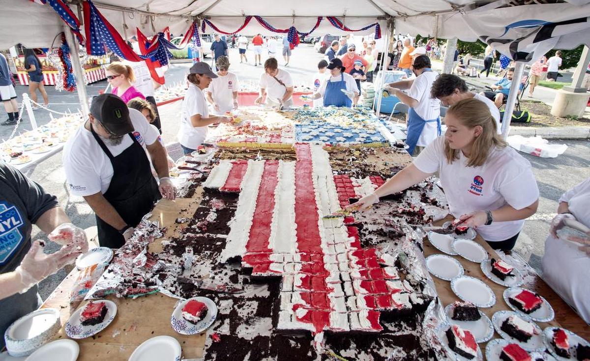 Volunteers help to cut the giant American Flag cake during the Central PA 4th Fest on Wednesday, July 4, 2018. The annual event is smaller this year due to dwindling volunteers.