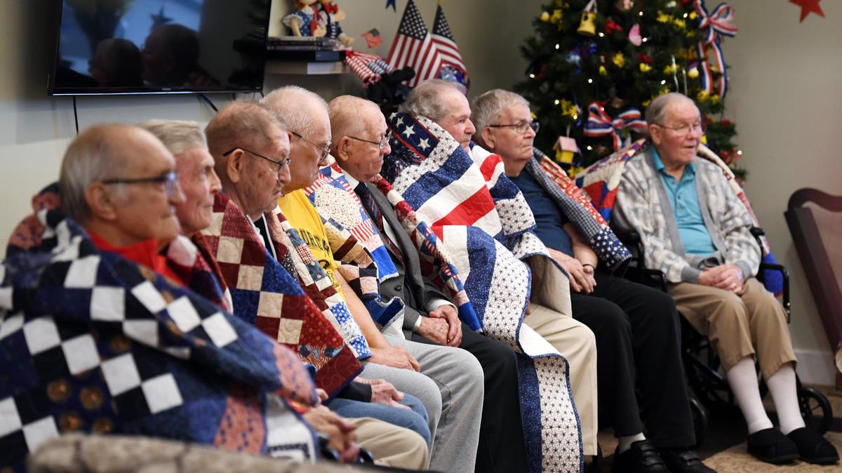 Veterans sit wrapped in their new quilts during the Quilts of Valor quilt presentation at Wynwood House.