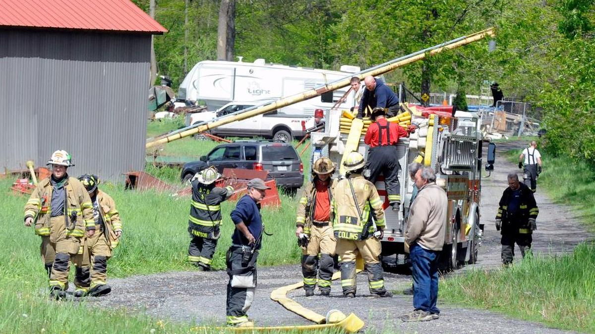 Fire crews pack up their equipment after extinguishing a blaze on the 100 block of Railroad Street near Blanchard on Monday. A fire official said homeowners were conducting a controlled burn on their property when gusty winds whipped the blaze, endangering three structures. Fire crews extinguished the blaze in about 15 minutes, saving the structures.