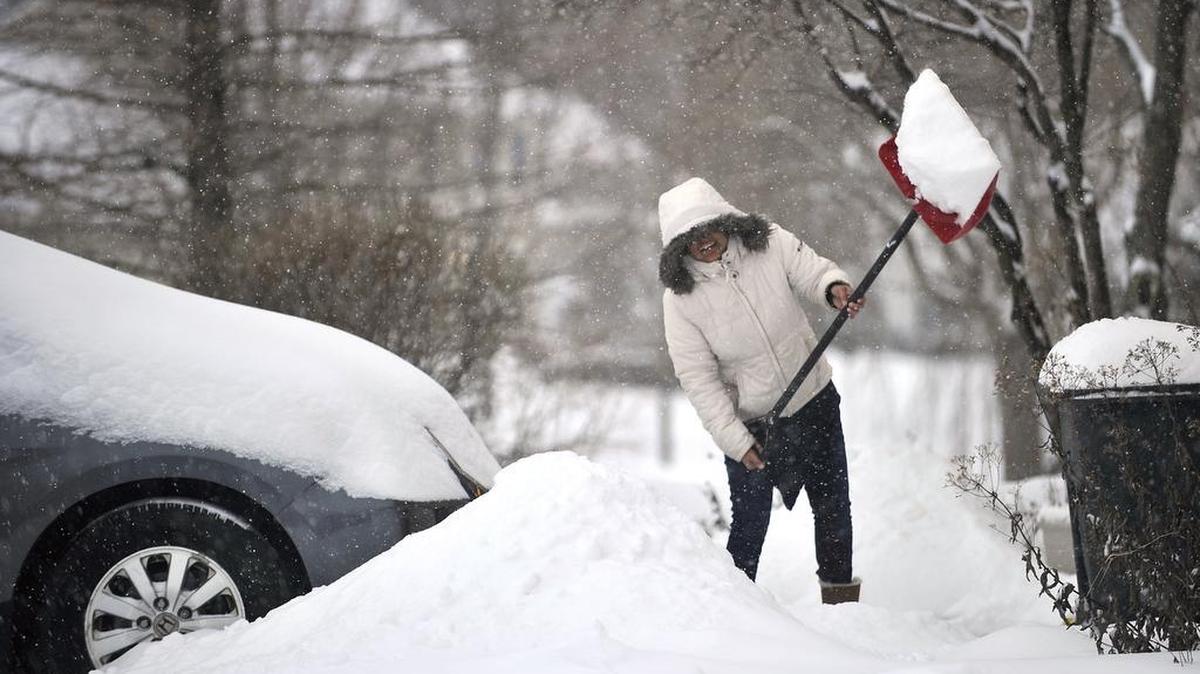 A woman shovels snow off her driveway in the GreenTree neighborhood.