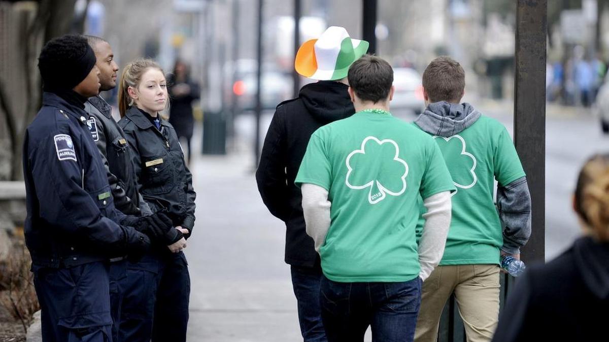 Students dressed in green walk by Penn State Auxiliary Cops on the corner of Beaver Avenue and Locust Lane during State Patty's Day on Saturday, February 23, 2013. This year in efforts to stop the student created holiday many bars were not open.