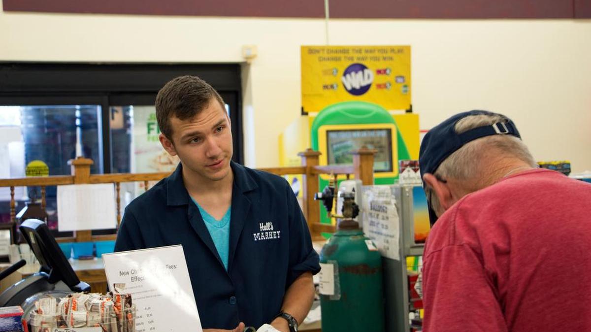 Justin Kobularcik, a student at Bald Eagle Area High School, works the register at Hall’s Market in Snow Shoe. He said he does most of his banking online, so First National Bank’s departure will not affect him as much as his grandparents.