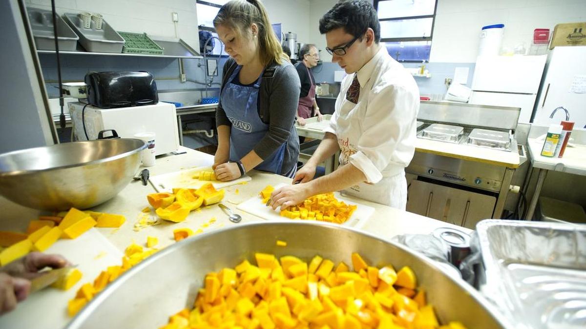 Mormon missionaries Sister Jarvis and Elder Ison cut squash while preparing for the Thanksgiving dinner at St. Andrew’s Episcopal Church on Tuesday, Nov. 24, 2015.