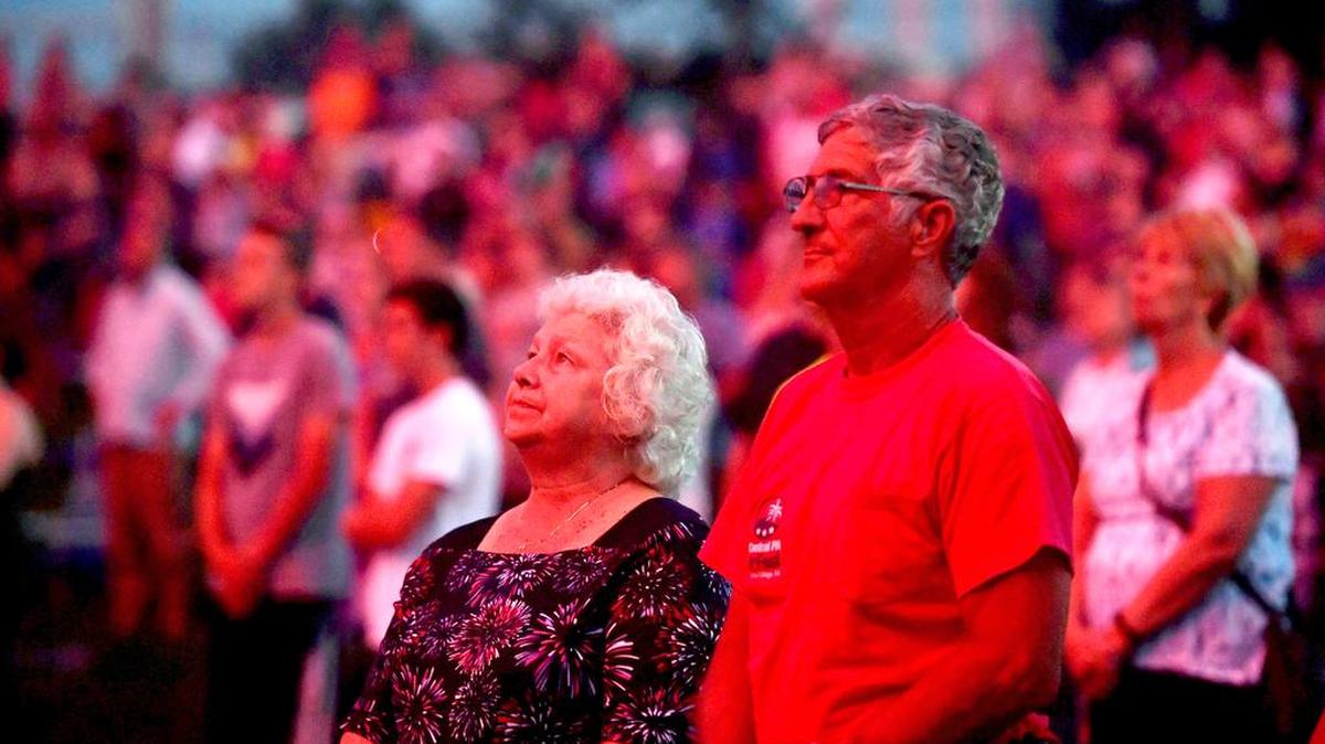 Longtime 4th Fest volunteer Bryce Boyer and his wife stand to watch as the flag is lowered and the first fireworks are launched on Tuesday.